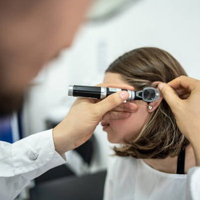 Doctor/otolaryngologist using an otoscope in a patient's ear at medical clinic