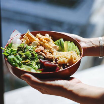 Healthy salad with fresh vegetables.View from above. Closeup image of a woman holding and eating chicken salad